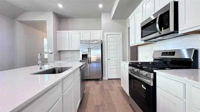 a kitchen with stainless steel appliances a stove a microwave and sink