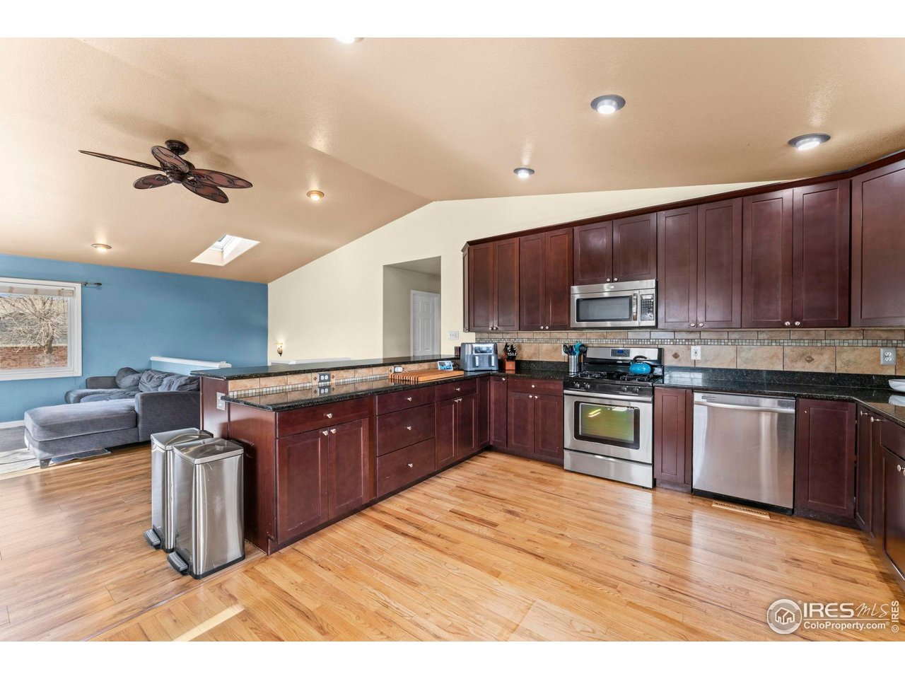 124 Adams Way Firestone, CO 80520 - Photo 11 of 34 a kitchen with stainless steel appliances kitchen island granite countertop a sink dishwasher a stove with wooden cabinets