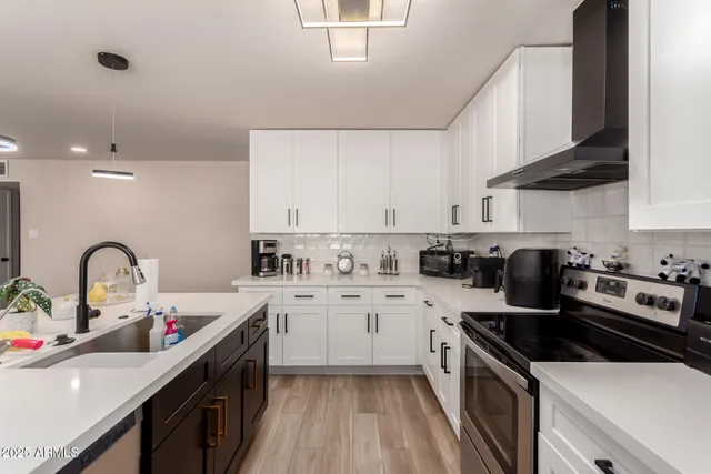 a kitchen with a sink a stove top oven and wooden floors