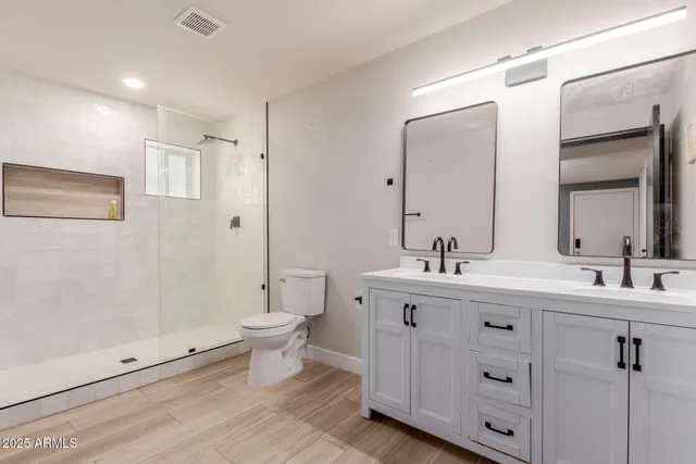 a bathroom with a double vanity sink toilet and shower
