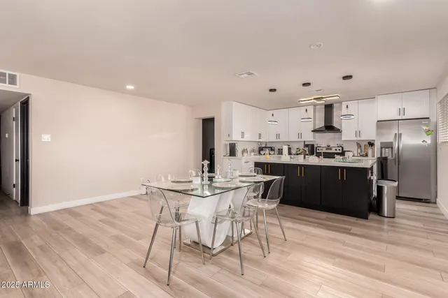 a kitchen with stainless steel appliances kitchen island granite countertop a refrigerator a stove a sink and white cabinets with wooden floor