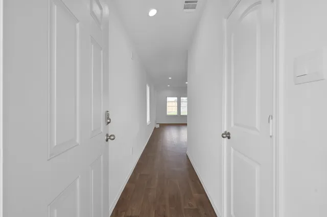 a view of a hallway with wooden floor and a shower