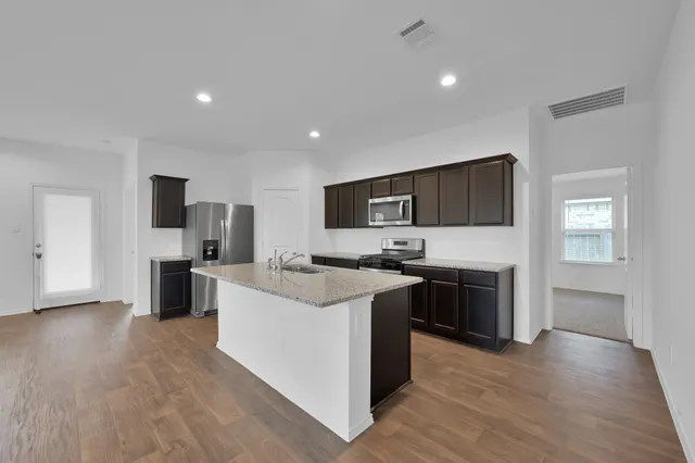 a large kitchen with stainless steel appliances and a wooden floor