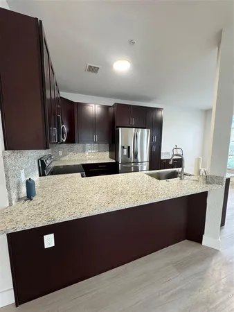 a kitchen with granite countertop a sink dishwasher stove and cabinets