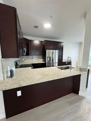 a kitchen with granite countertop a sink dishwasher stove and cabinets