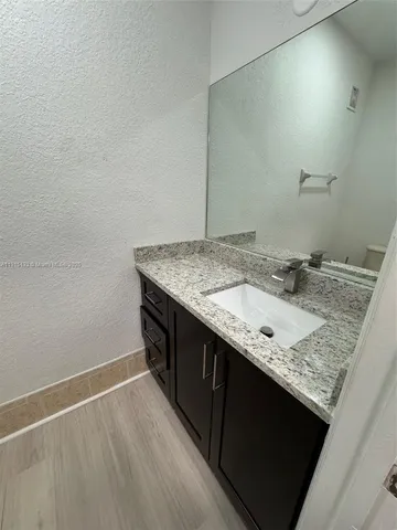 a bathroom with a granite countertop sink and a mirror