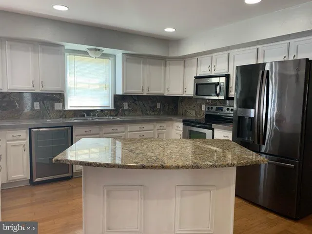 a kitchen with kitchen island granite countertop a sink stove refrigerator and cabinets