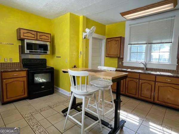 a kitchen with granite countertop a stove a sink and a refrigerator