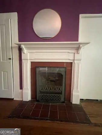 a view of an empty room with wooden floor and a fireplace