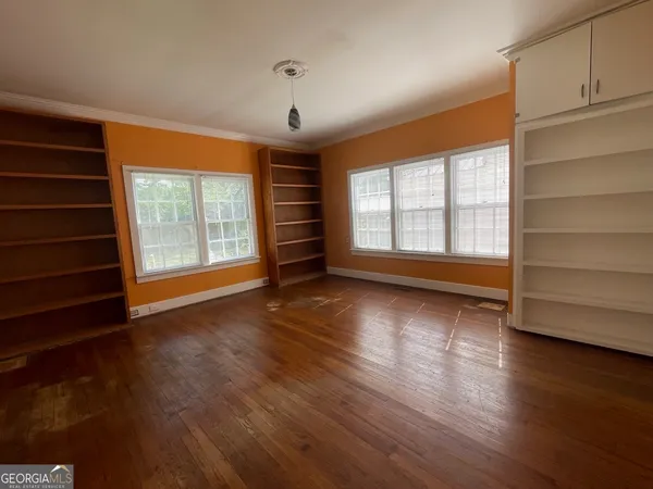 an empty room with wooden floor and windows
