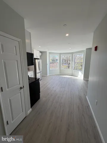 a view of a kitchen with a refrigerator a stove top oven and wooden floor