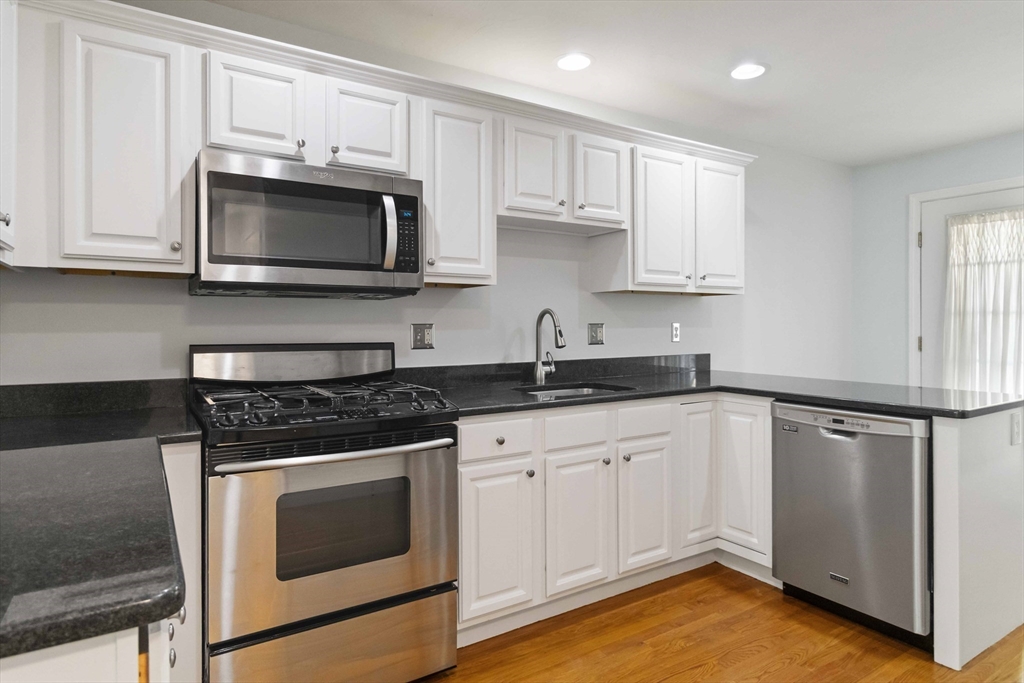 47 Alder Street, Unit 6 Waltham, MA 02453 - Photo 11 of 34 a kitchen with white cabinets and stainless steel appliances