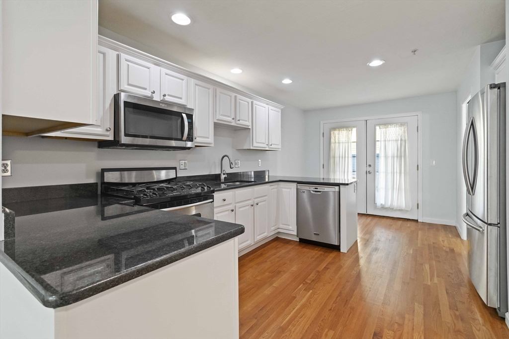 47 Alder Street, Unit 6 Waltham, MA 02453 - Photo 5 of 34 a kitchen with stainless steel appliances white cabinets a sink a stove a microwave and wooden floors