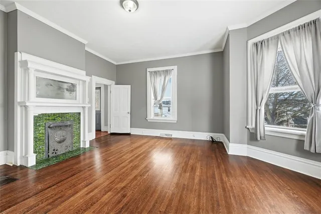 an empty room with wooden floor fireplace and windows