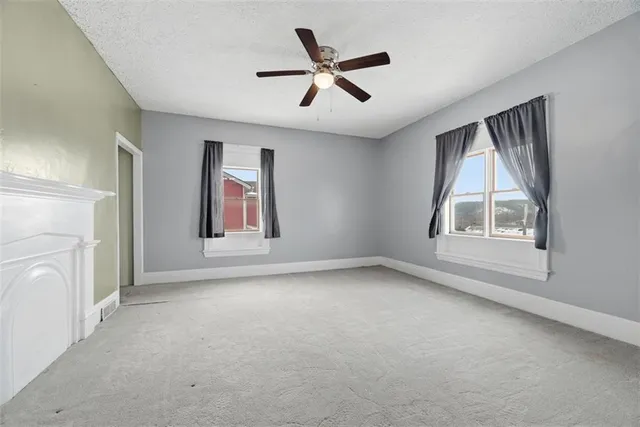 an empty room with windows and ceiling fan