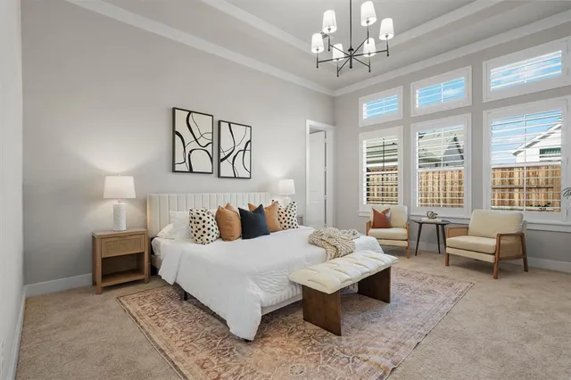 a spacious bedroom with a bed a couch and a chandelier