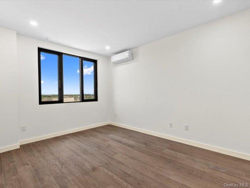 124-28 Queens Boulevard, Unit 9D Queens, NY 11415 - Photo 8 of 14 Empty room with wood finished floors, a wall unit AC, and recessed lighting