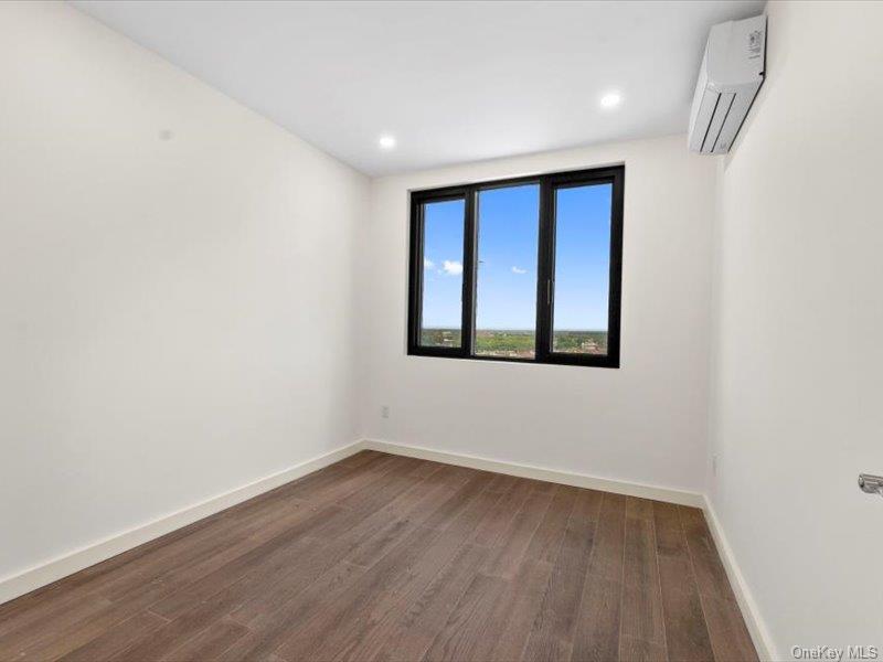 124-28 Queens Boulevard, Unit 9D Queens, NY 11415 - Photo 10 of 14 Unfurnished room with dark wood-style flooring, an AC wall unit, and recessed lighting