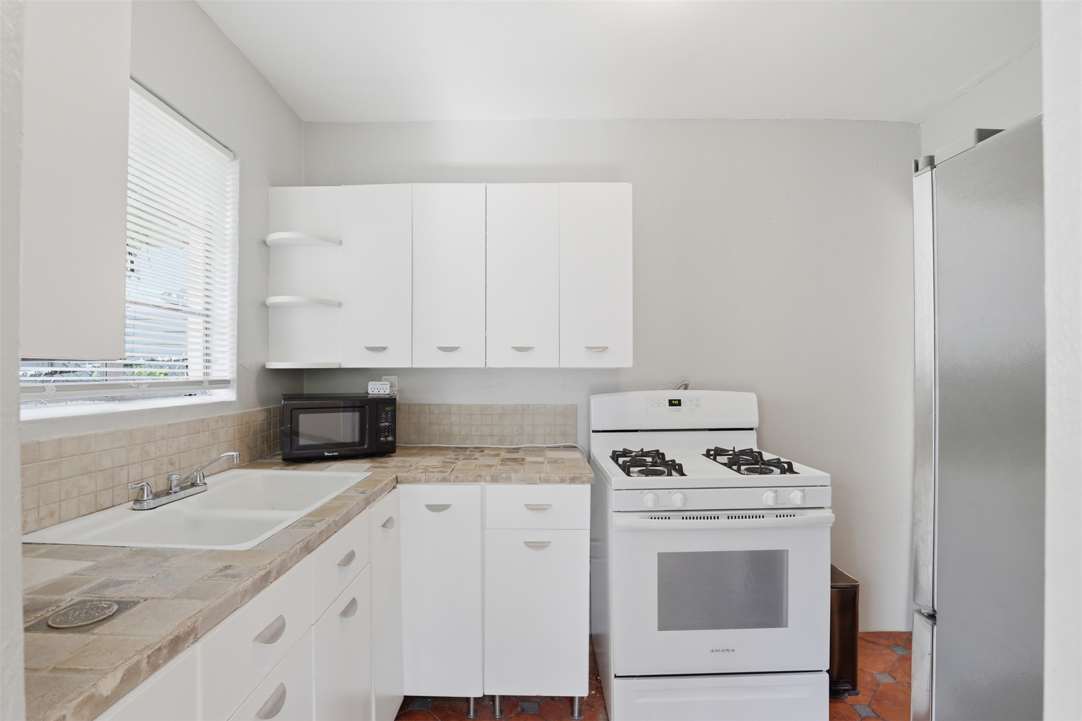 3901 Wrightwood Road, Unit A Austin, TX 78722 - Photo 7 of 11 Kitchen featuring white cabinetry, white gas range, and a stainless steel refrigerator.
