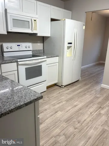 a kitchen with stainless steel appliances granite countertop a refrigerator sink and white cabinets