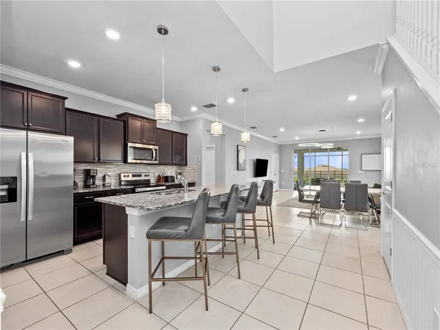 a kitchen with stainless steel appliances kitchen island granite countertop a stove a refrigerator a oven a sink with a dining table and chairs