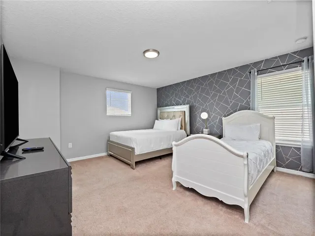 a spacious bedroom with two beds and a flat screen tv