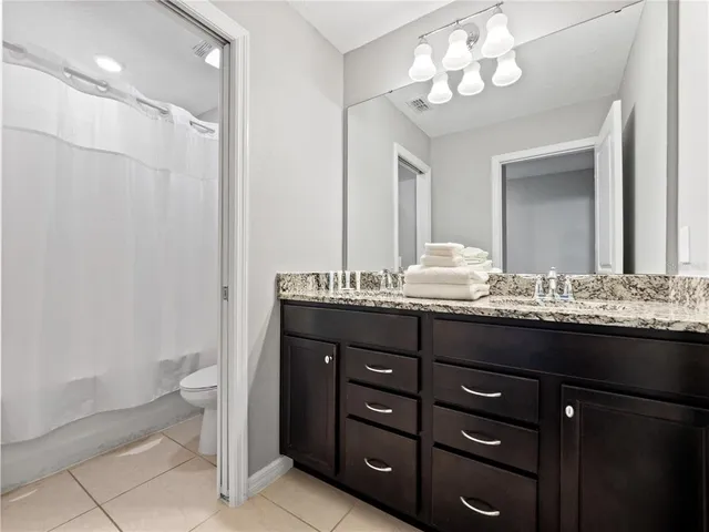 a bathroom with a granite countertop sink a toilet and a mirror