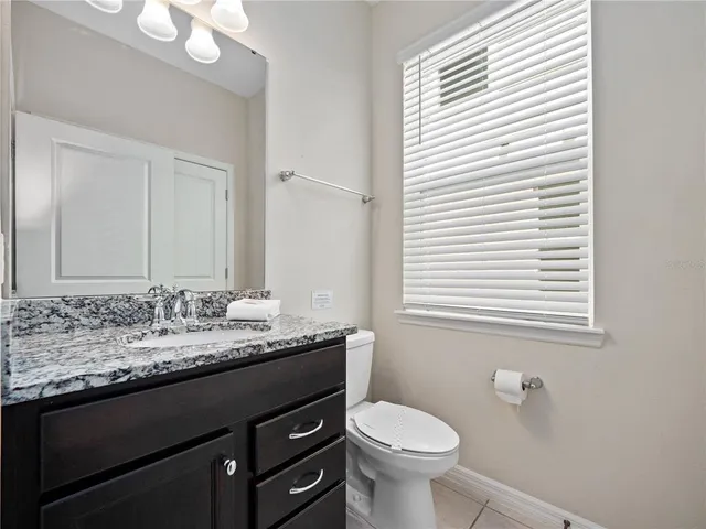 a bathroom with a granite countertop sink toilet and mirror
