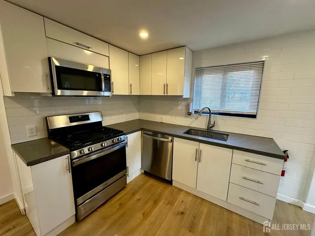 a kitchen with granite countertop a sink cabinets and stainless steel appliances