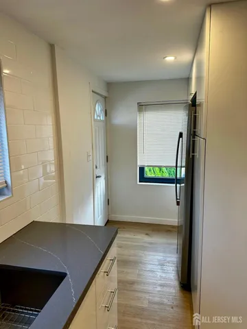 a view of a refrigerator a window and wooden floor