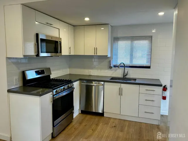 a kitchen with granite countertop cabinets stainless steel appliances and wooden floor