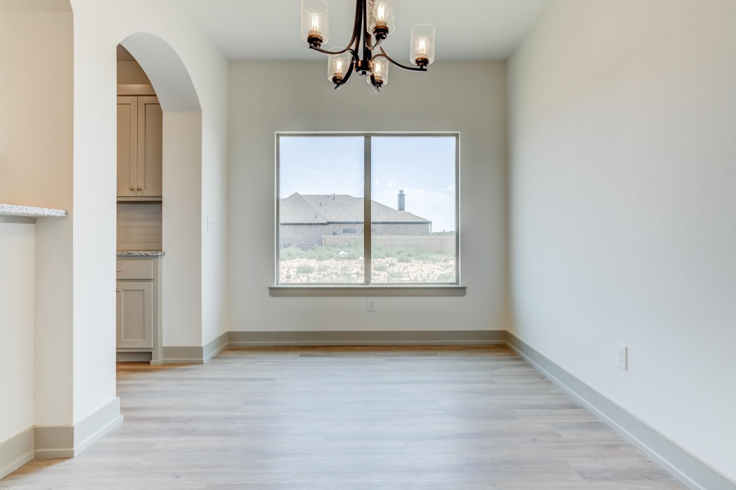 7007 18th Street Lubbock, TX 79416 - Photo 9 of 34 an empty room with wooden floor chandelier and windows