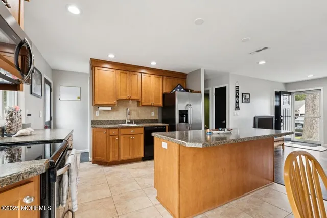 a kitchen with stainless steel appliances granite countertop a sink refrigerator and cabinets
