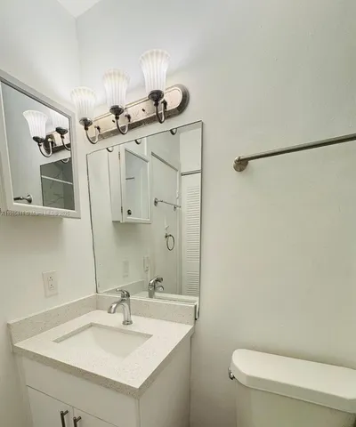 a bathroom with a sink a toilet a mirror and shower