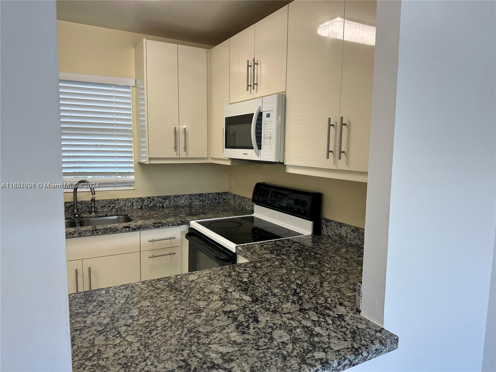 Sequoia Gardens Condominiums Deerfield Beach, FL 33441 - Photo 7 of 25 a kitchen with stainless steel appliances granite countertop a stove a sink and a microwave