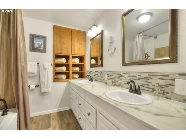 a bathroom with a sink double vanity granite tub shower and a mirror