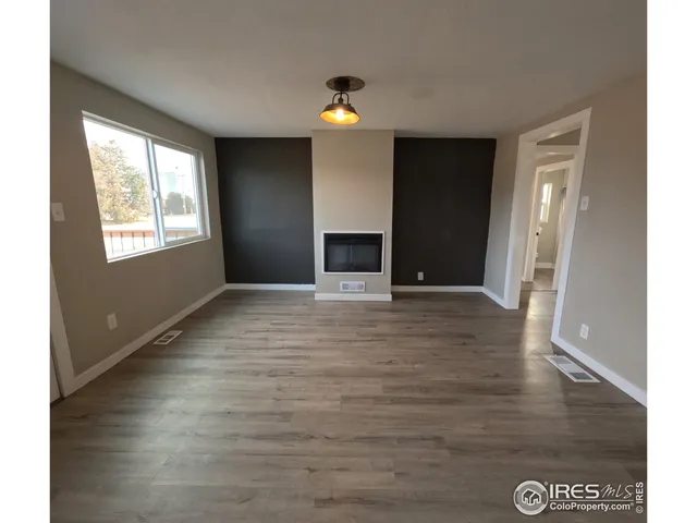 a view of an empty room with window and wooden floor