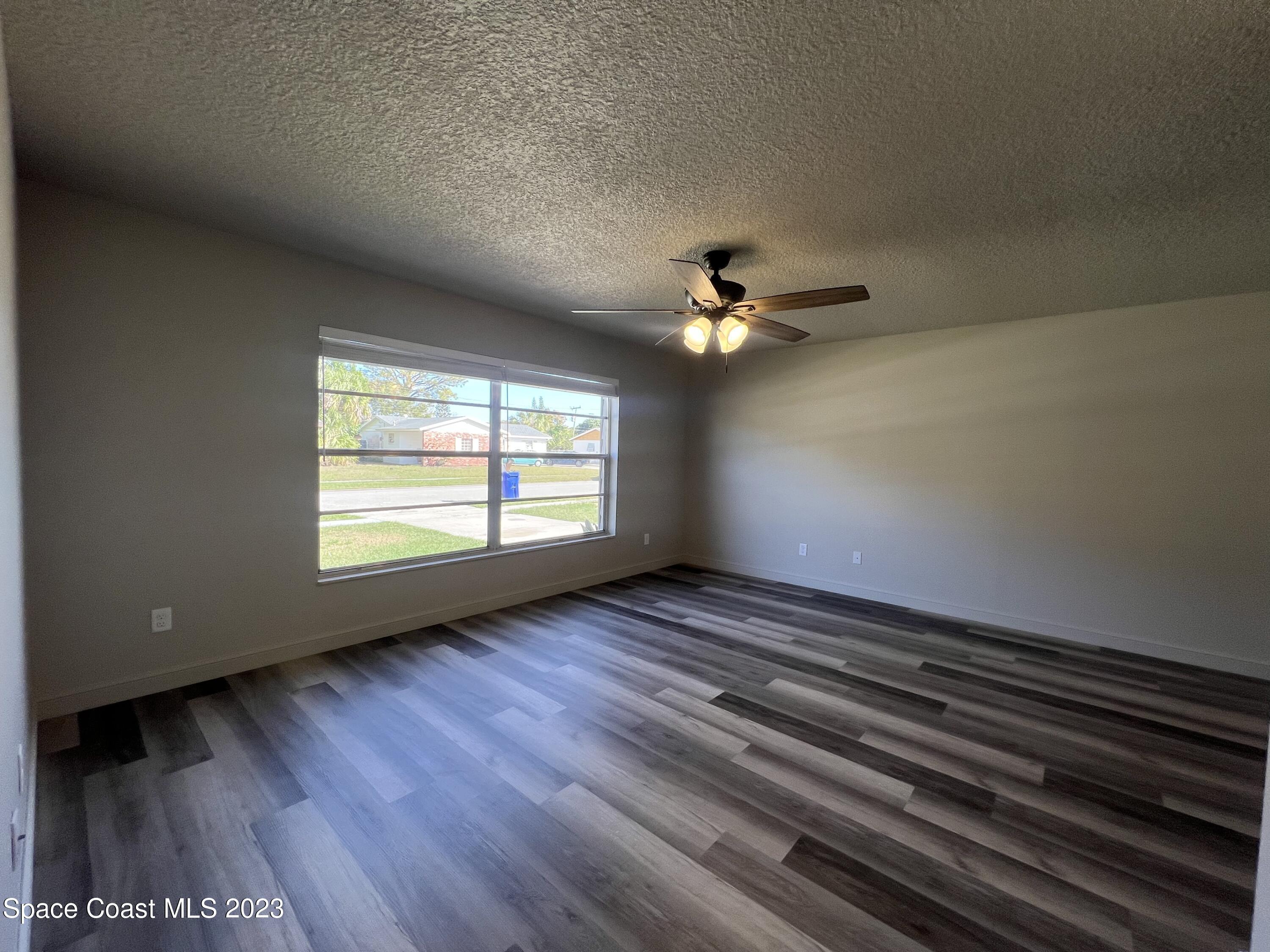 1095 Coronado Drive Rockledge, FL 32955 - Photo 6 of 28 a view of an empty room with wooden floor and a window