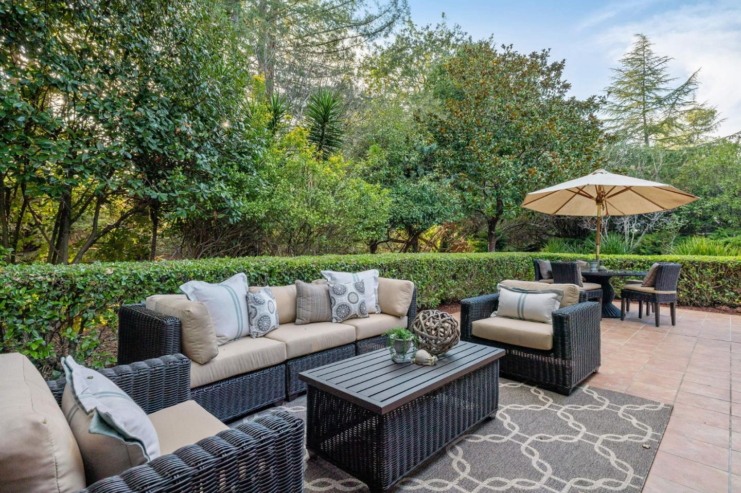 16 Valley Road Atherton, CA 94027 - Photo 20 of 100 a view of a patio with couches and a table and chairs under an umbrella with large trees