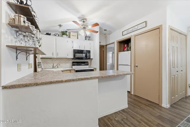 a kitchen with stainless steel appliances granite countertop a sink a stove a refrigerator a microwave oven with white cabinets and granite countertops