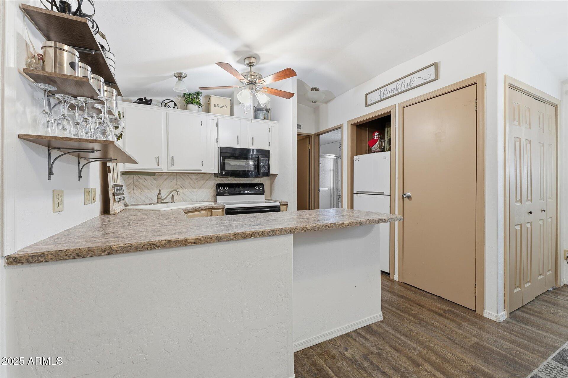 5735 East McDowell Road, Unit 243 Mesa, AZ 85215 - Photo 12 of 42 a kitchen with stainless steel appliances granite countertop a sink a stove a refrigerator a microwave oven with white cabinets and granite countertops