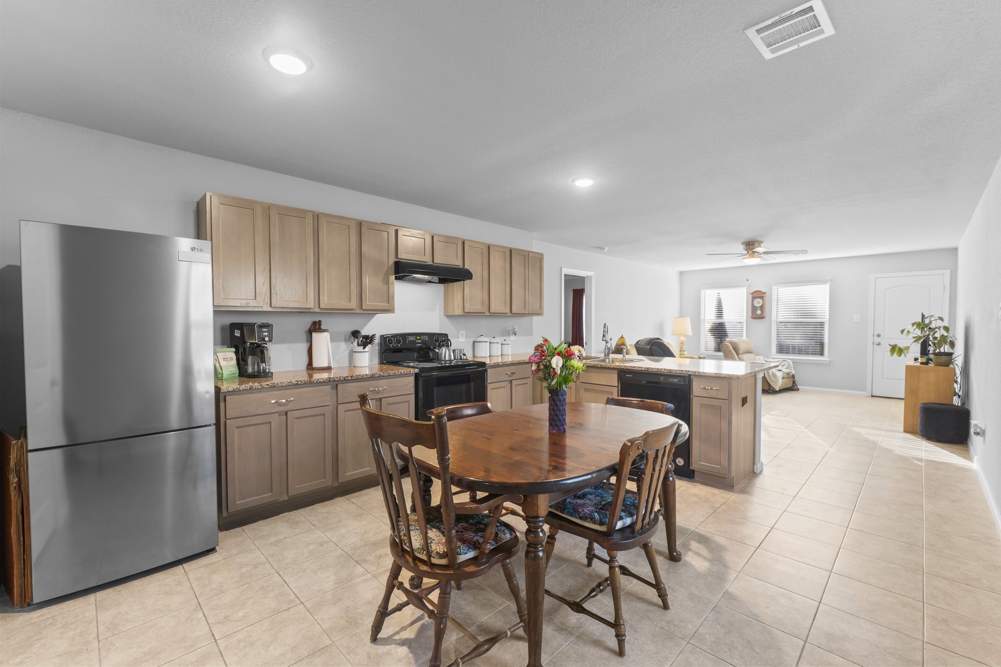 15120 Arrowhead Loop East Willis, TX 77378 - Photo 6 of 22 a kitchen with a dining table chairs refrigerator and cabinets