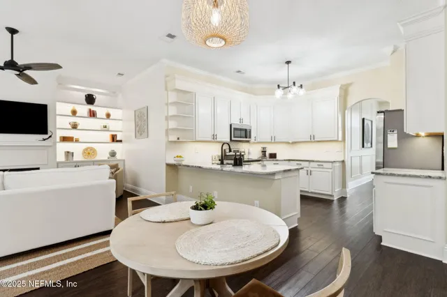 a open dining room with stainless steel appliances kitchen island granite countertop a sink a stove a dining table and chairs