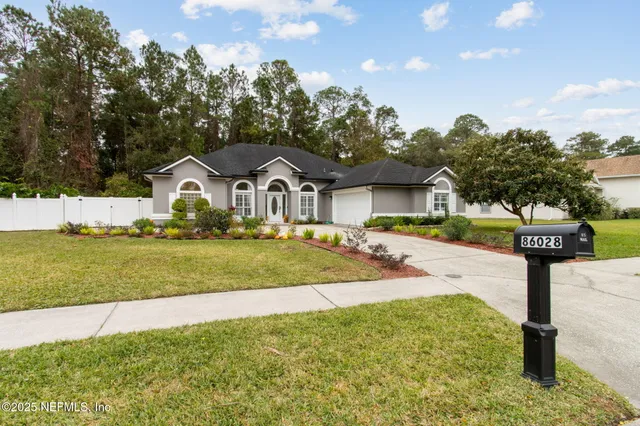 a view of a house with a yard and large tree