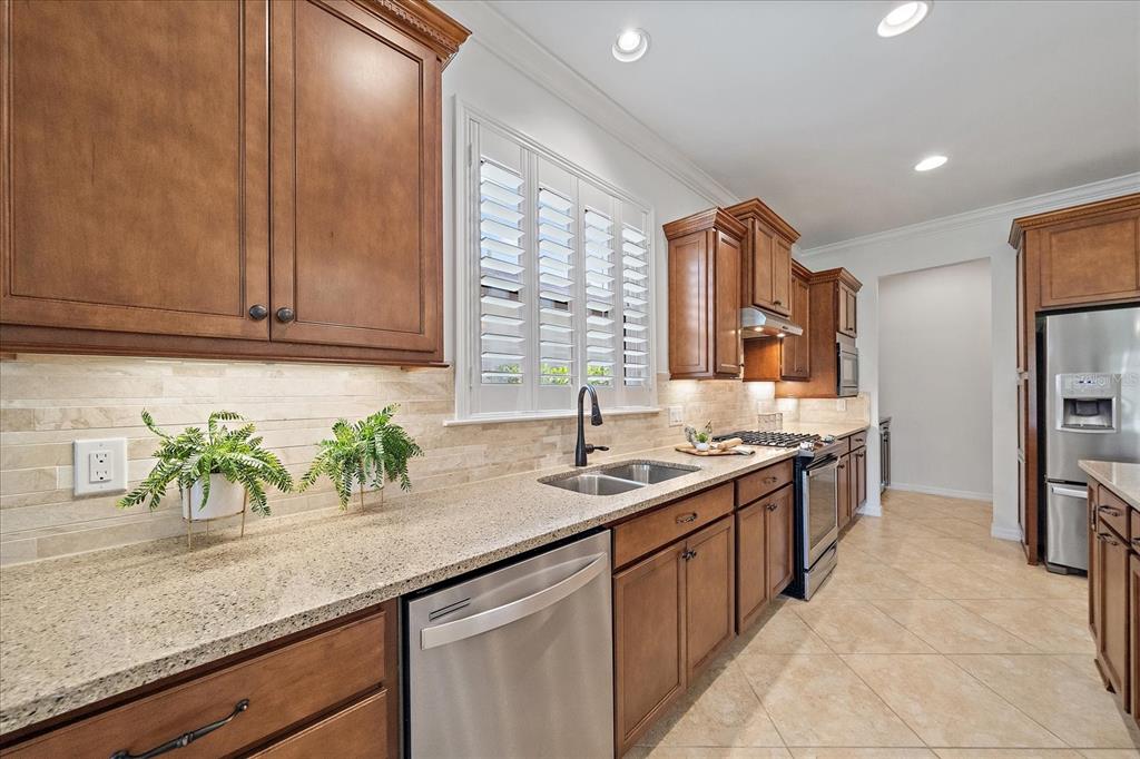 6713 Chester Trail Lakewood Ranch, FL 34202 - Photo 9 of 45 a kitchen with granite countertop stainless steel appliances a sink stove and cabinets