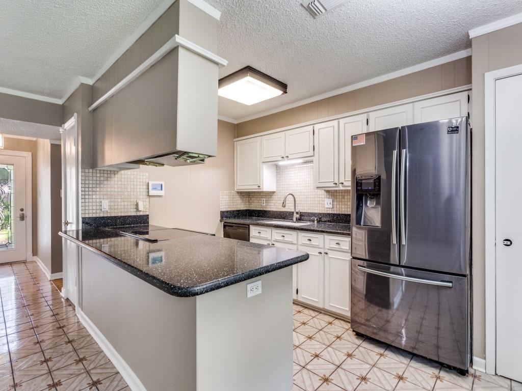 1216 Manning Street Benbrook, TX 76126 - Photo 8 of 26 Kitchen with stainless steel fridge with ice dispenser, tasteful backsplash, a peninsula, crown molding, and dark stone countertops