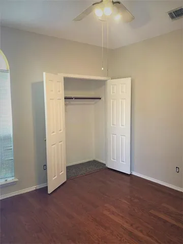 an empty room with wooden floor and chandelier fan