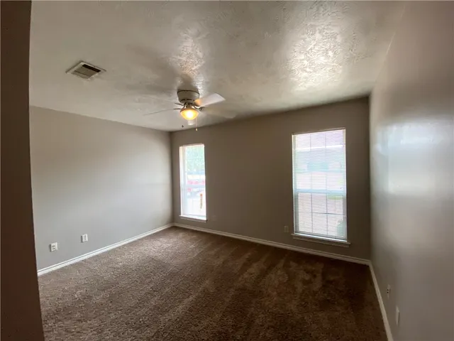 en empty room with windows and chandelier fan