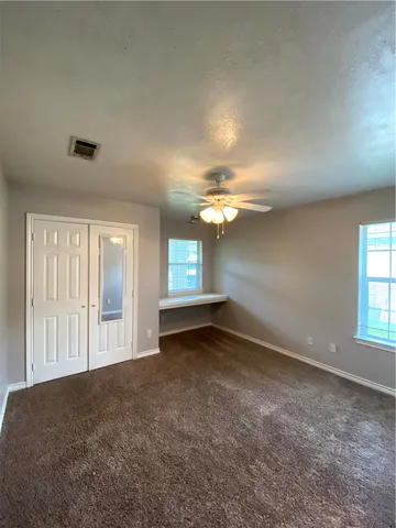 an empty room with windows and ceiling fan