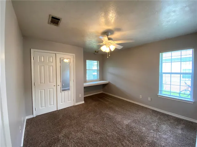an empty room with windows and fan